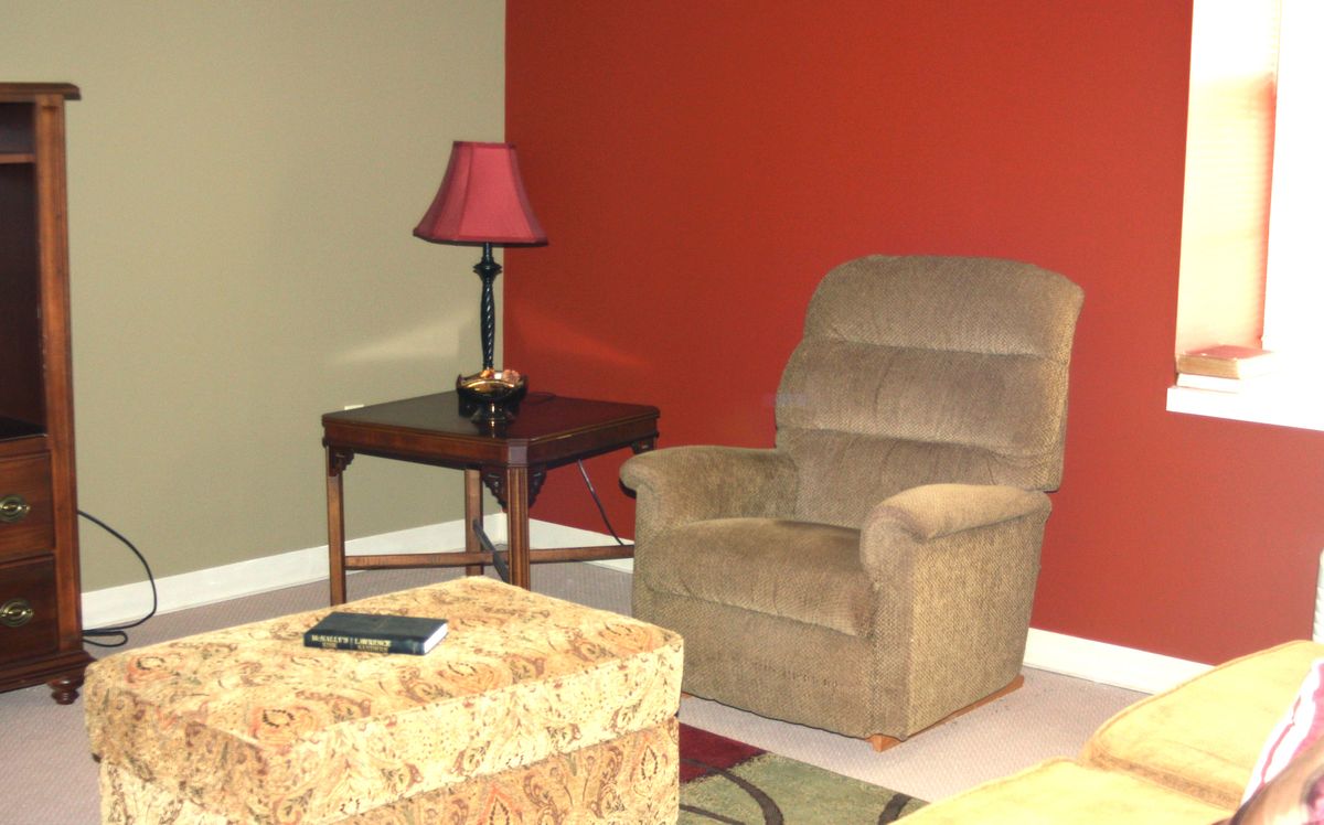 A cozy living room corner with an armchair and side table featuring a lamp.