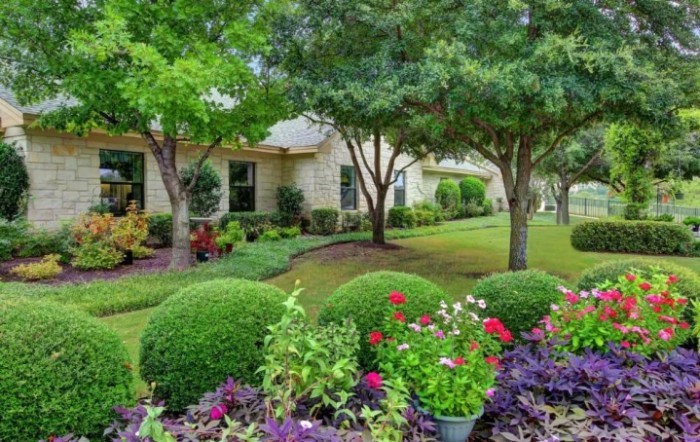 A beautifully landscaped garden with a variety of flowers and trees in front of a house.