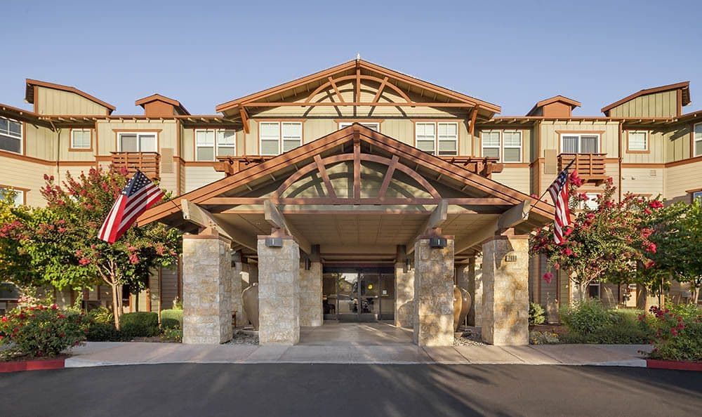 The entrance of a hotel adorned with flags and featuring a prominent wooden structure.