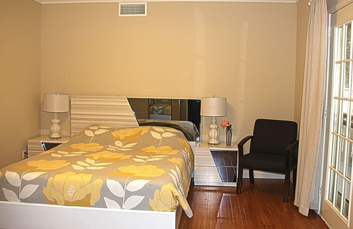 A cozy bedroom with a floral bedspread, bedside table, and a lamp.