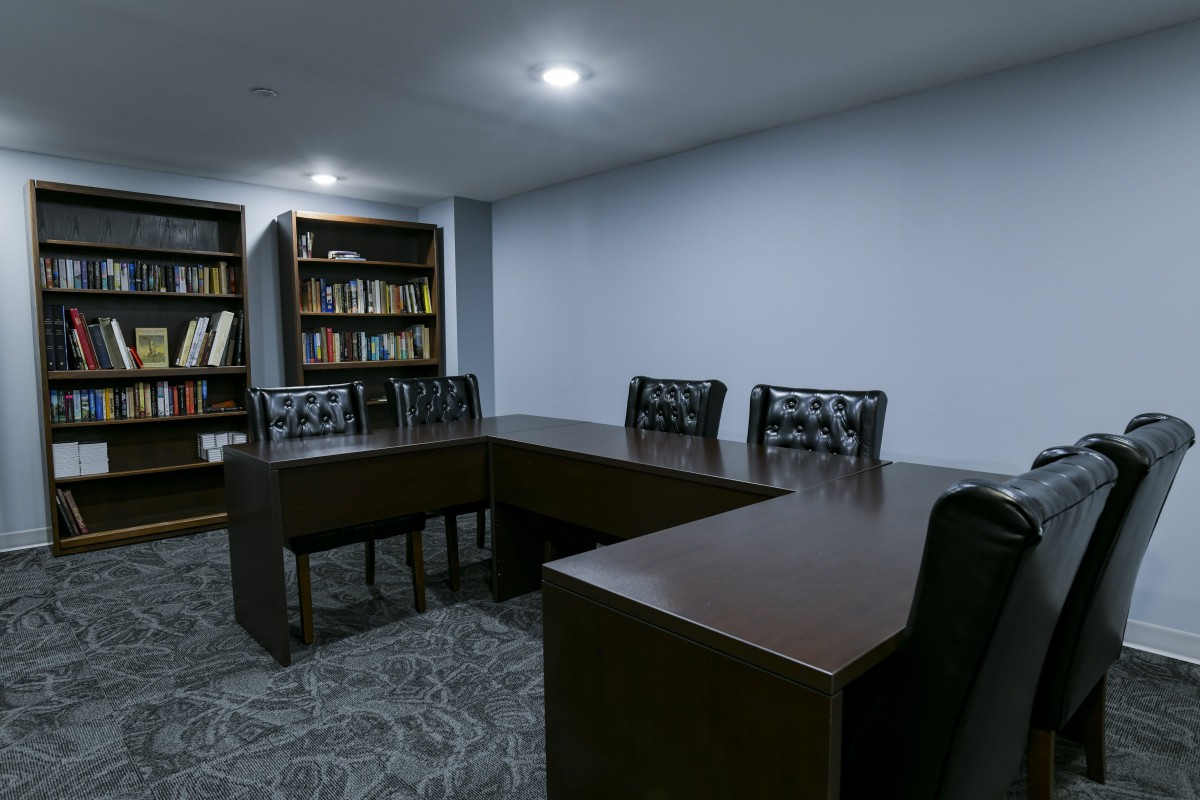 A conference room with a large table, chairs, and bookshelves.
