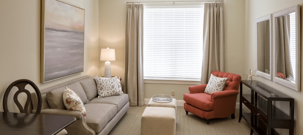 A cozy living room with a gray sofa, red armchair, and soft lighting.