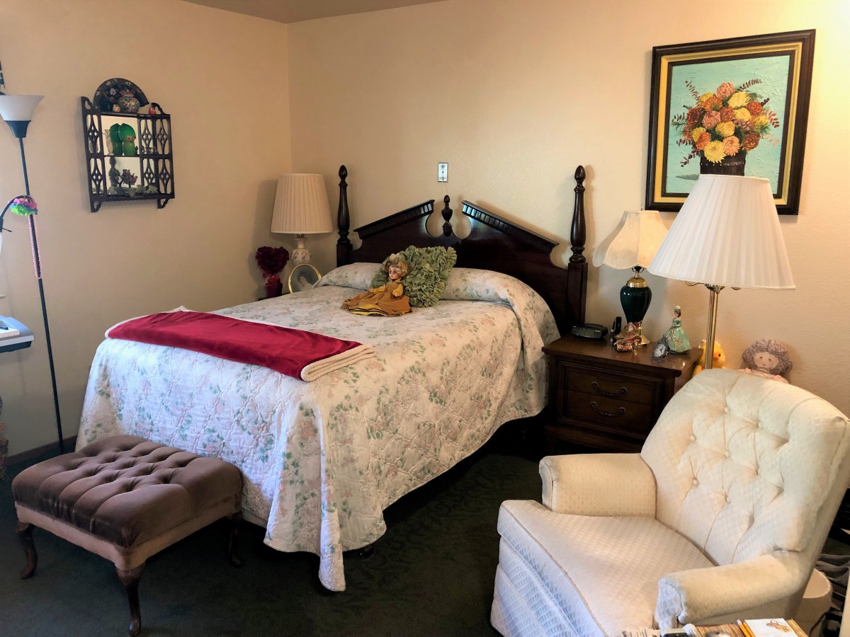 A cozy bedroom with a wooden bed, upholstered chair, and elegant decor.