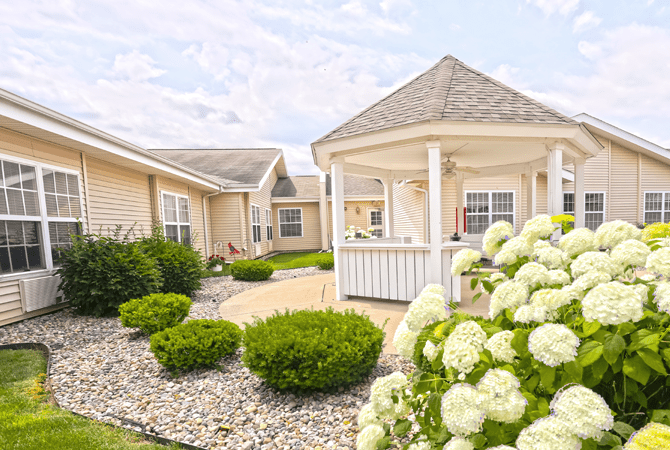 A peaceful garden with a gazebo surrounded by lush landscaping and blooming flowers.