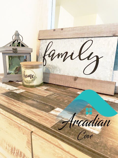 A charming home decor setup featuring a family sign, candle, and lantern on a wooden surface.
