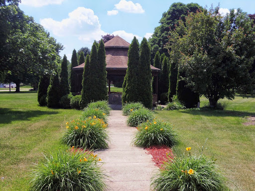 A picturesque garden pathway leading to a charming house, surrounded by neatly trimmed trees and colorful flower beds.