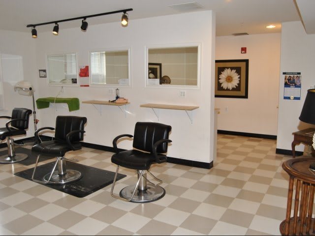 A modern hair salon with empty styling stations and sleek black chairs.