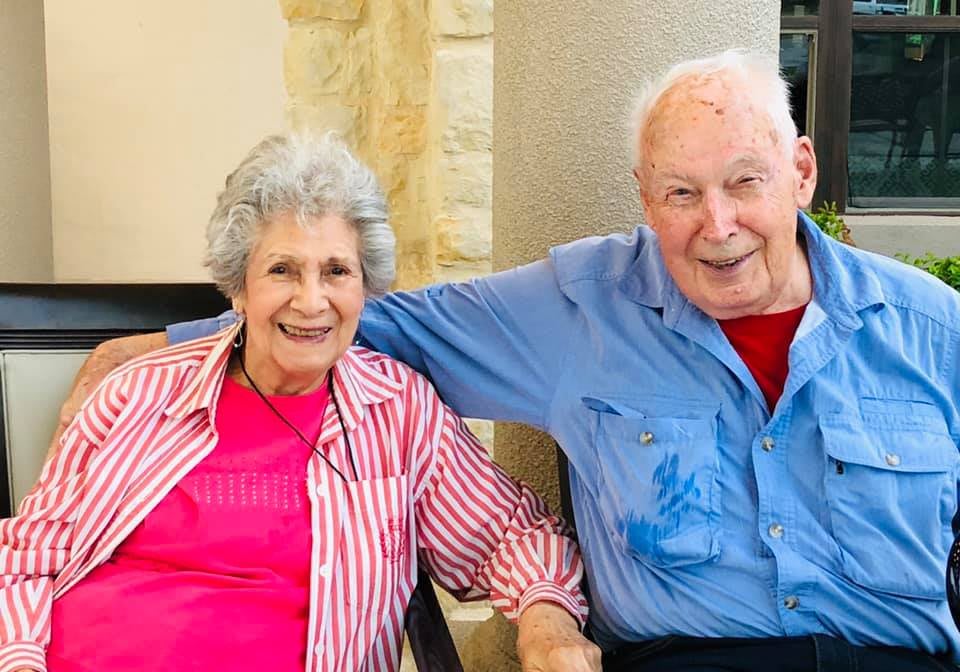 An elderly couple sitting together and smiling indoors.