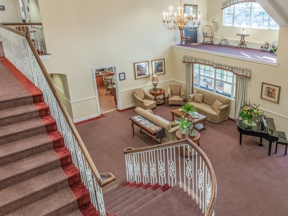 A spacious living room with a grand staircase and elegant chandelier.