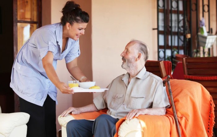 A caregiver assisting an elderly man with a meal at home.
