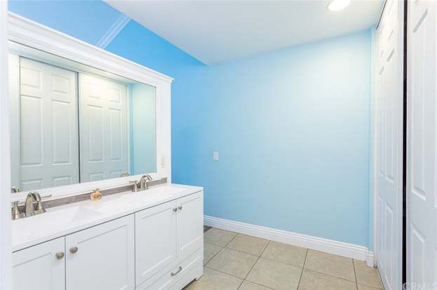 A bright bathroom with blue walls, a white vanity, and tiled flooring.