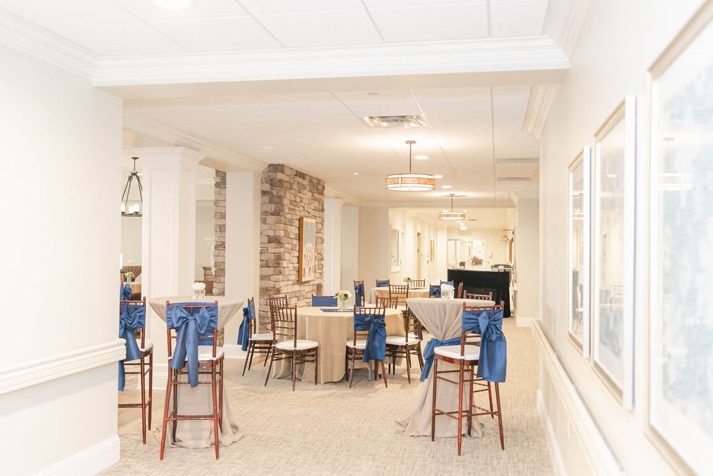 A bright event space with tables and chairs, detailed with blue decorations.