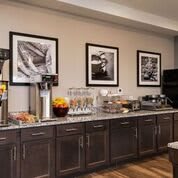 A modern hotel breakfast area featuring a buffet with drinks and food options.
