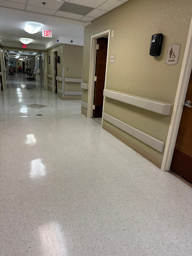 A quiet corridor in a hospital with doors leading to patient rooms.