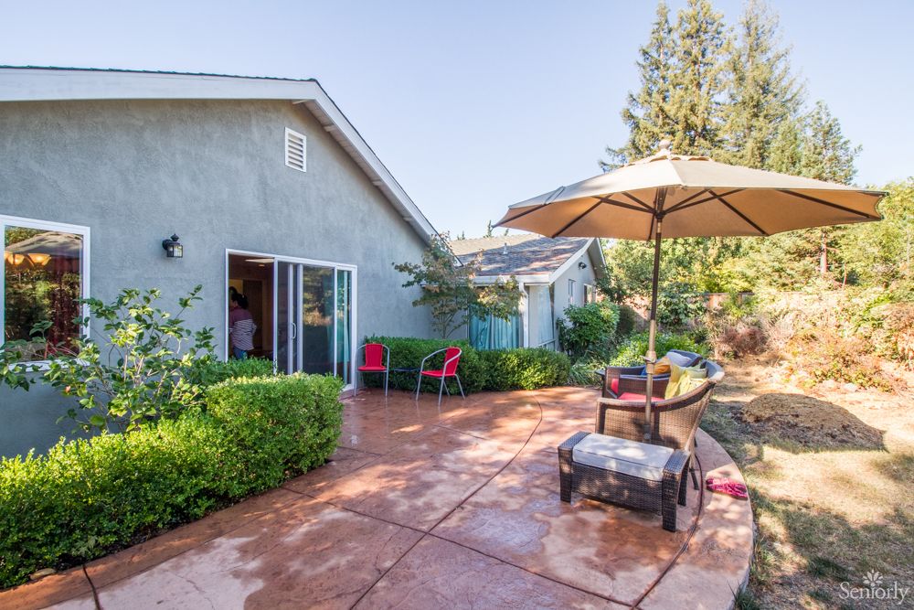 A sunny backyard patio with outdoor furniture and an umbrella.