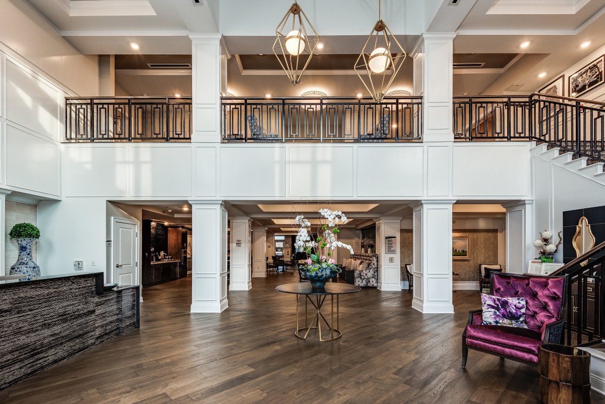 A luxurious and spacious lobby with elegant chandeliers and a wooden floor.