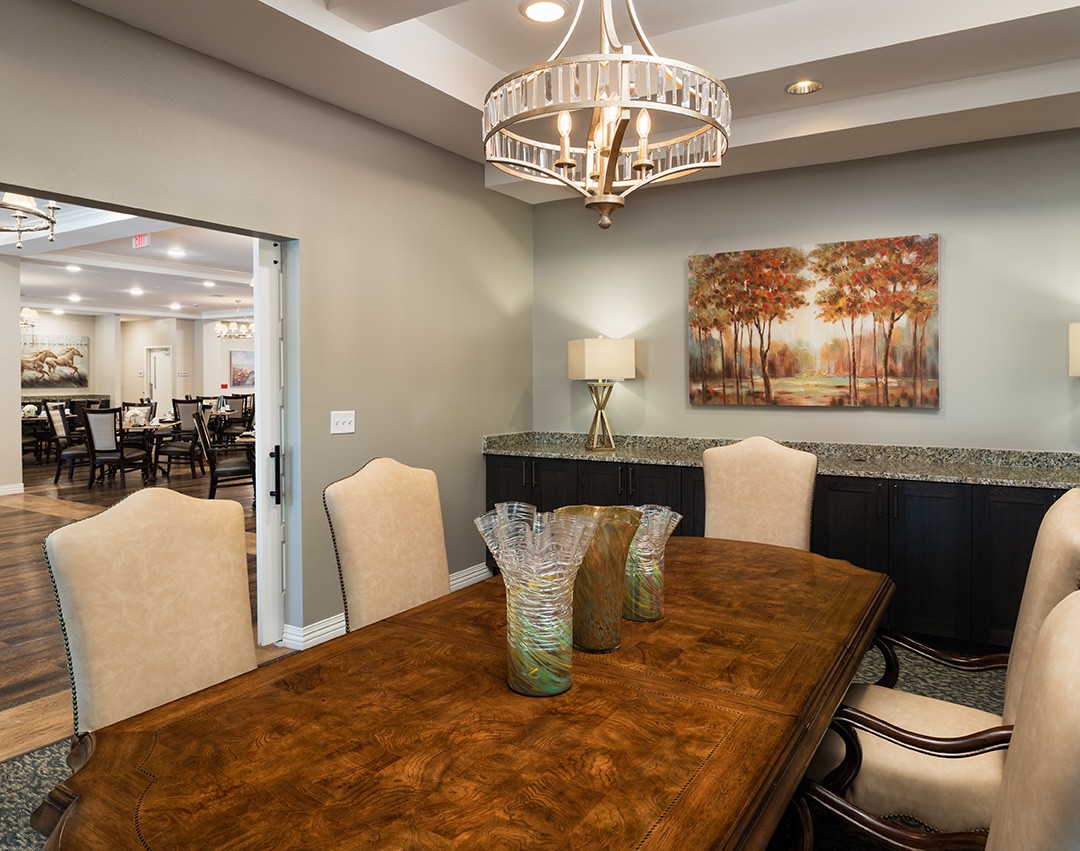 A stylish dining room featuring a wooden table with elegant chairs, a chandelier, and decorative elements.
