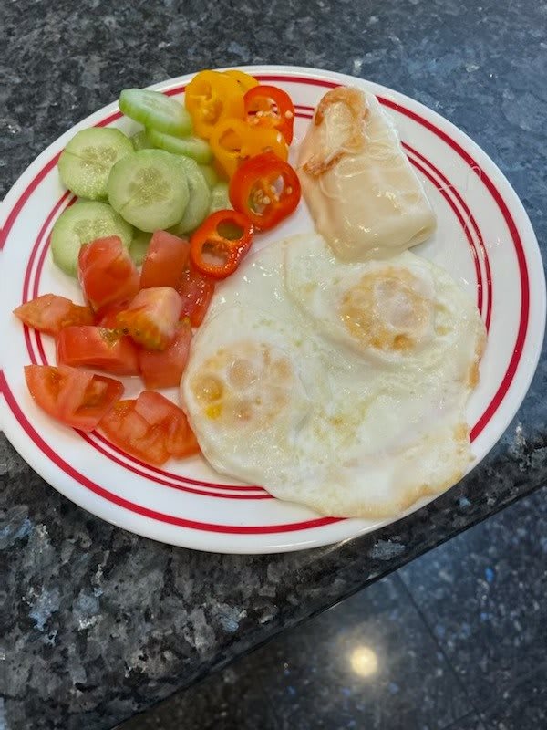 A colorful breakfast plate with fried eggs, toast, and fresh vegetables.