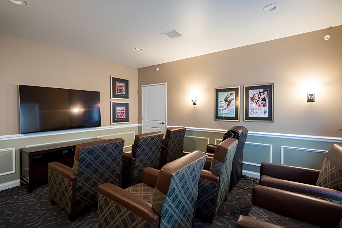 A cozy home theater room with comfortable armchairs, a large television, and decorative wall art.