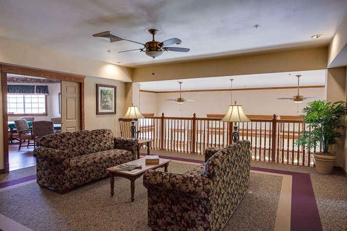 Cozy living room area with sofas, lamps, and a ceiling fan.