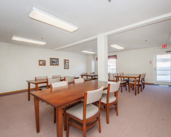 A spacious dining area featuring wooden tables and chairs, with bright lighting and simple decor.