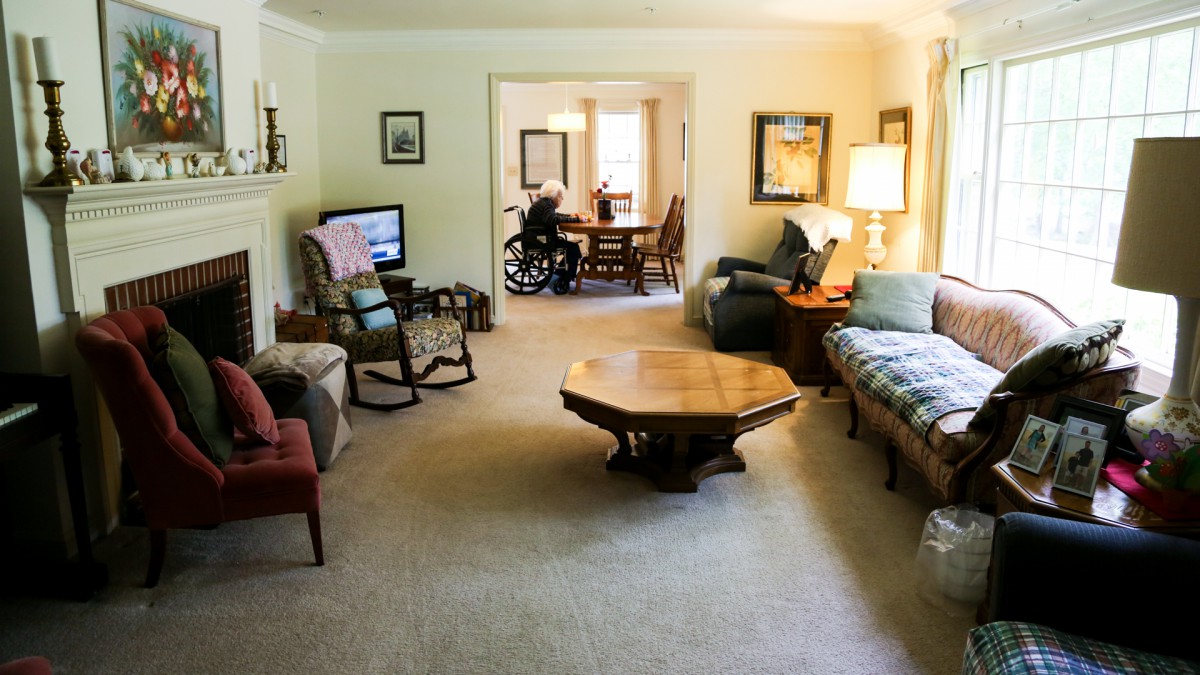 A cozy living room with various furniture pieces, including a wheelchair visible in the adjacent room.
