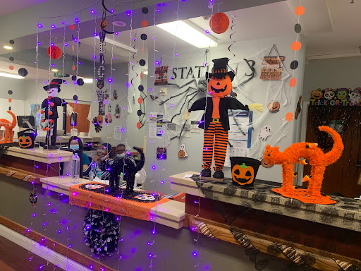A festive Halloween-themed display featuring a scarecrow, black cat, and colorful decorations.