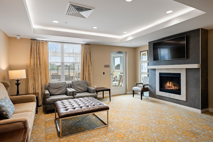 A modern living room featuring a fireplace, comfortable seating, and large windows.