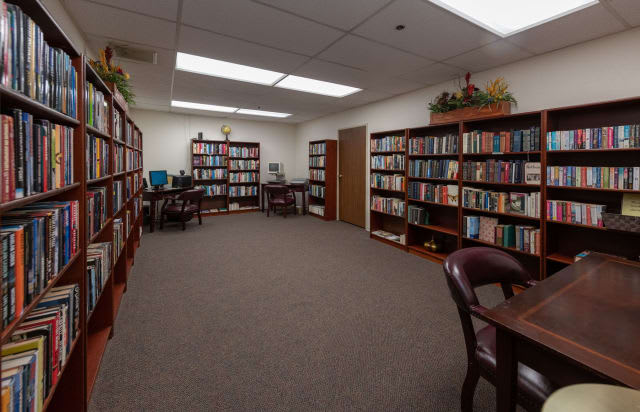 A quiet library room with bookshelves lining the walls and office furniture arranged for study or meetings.