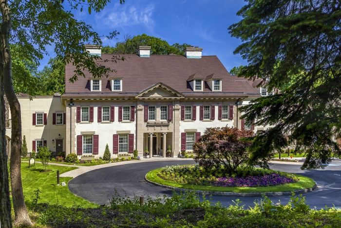 A luxurious mansion with beautiful landscaping and a circular driveway.