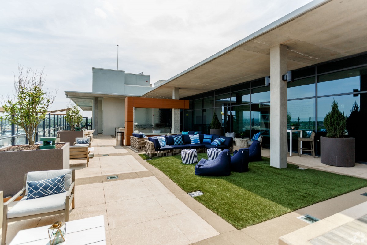 A modern rooftop terrace featuring comfortable bean bag seating and a small grass area.