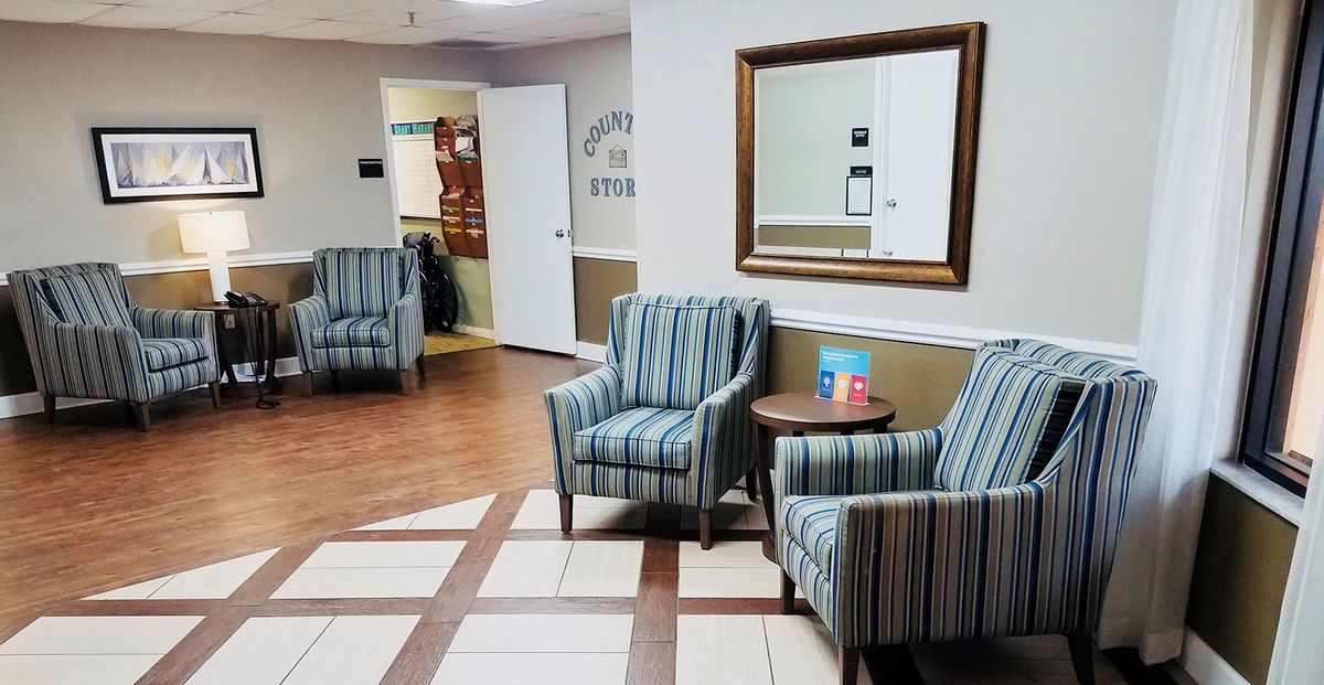 A cozy waiting room featuring striped chairs, a small table, and a mirror on the wall.