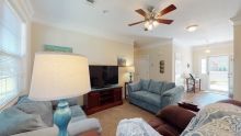 A cozy living room featuring a sofa, television, ceiling fan, and lamps.
