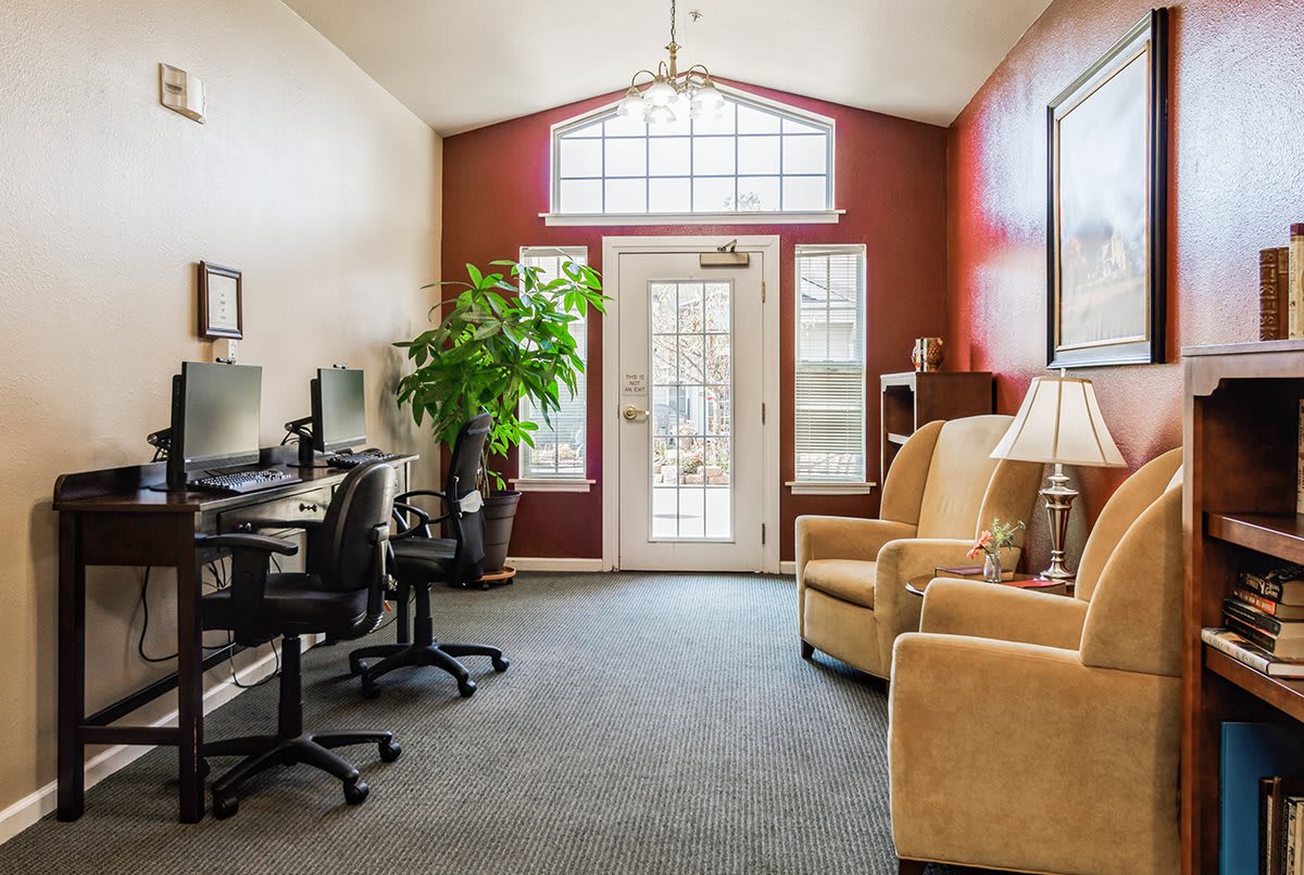 A cozy office space with computer stations, comfortable chairs, and large windows allowing natural light.