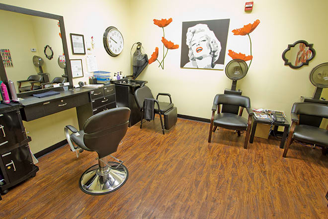 A stylish hair salon interior featuring chairs, mirrors, artwork, and salon equipment.