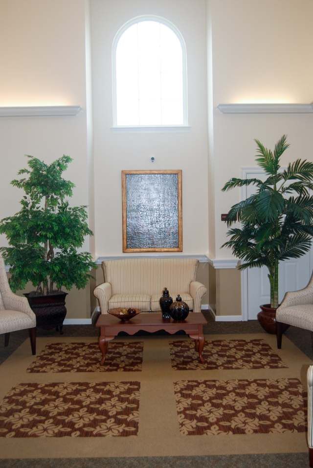 A well-decorated living room featuring a sofa, two armchairs, and indoor plants.