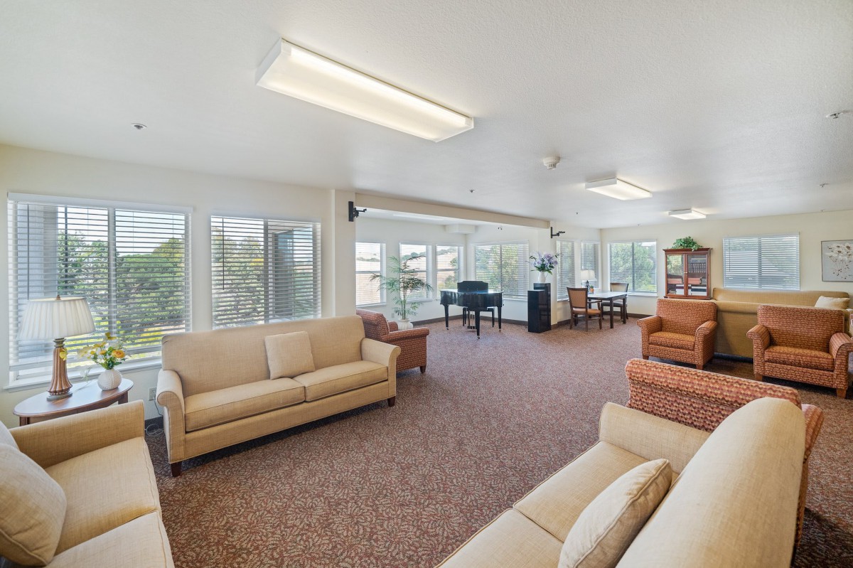 A spacious and well-lit living room with sofas and large windows allowing natural light to fill the space.