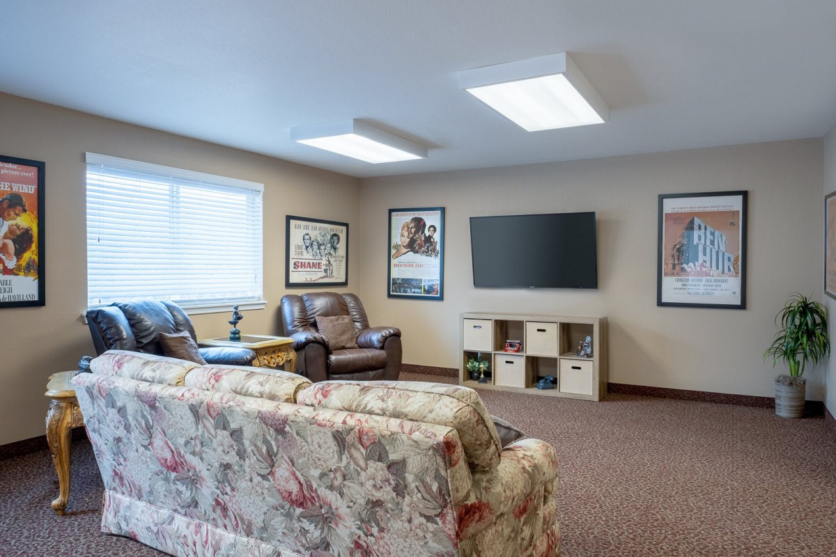 A cozy living room with a sofa and armchair facing a wall-mounted television.