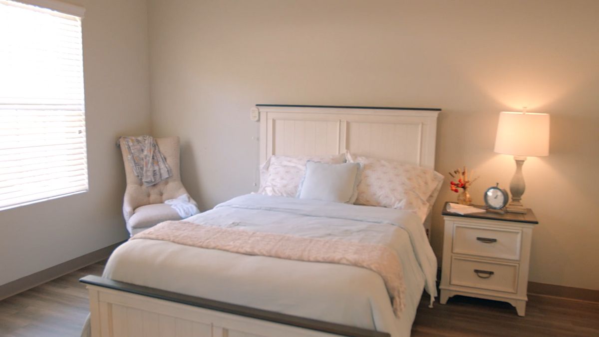 A cozy bedroom with a neatly made bed and soft lighting.