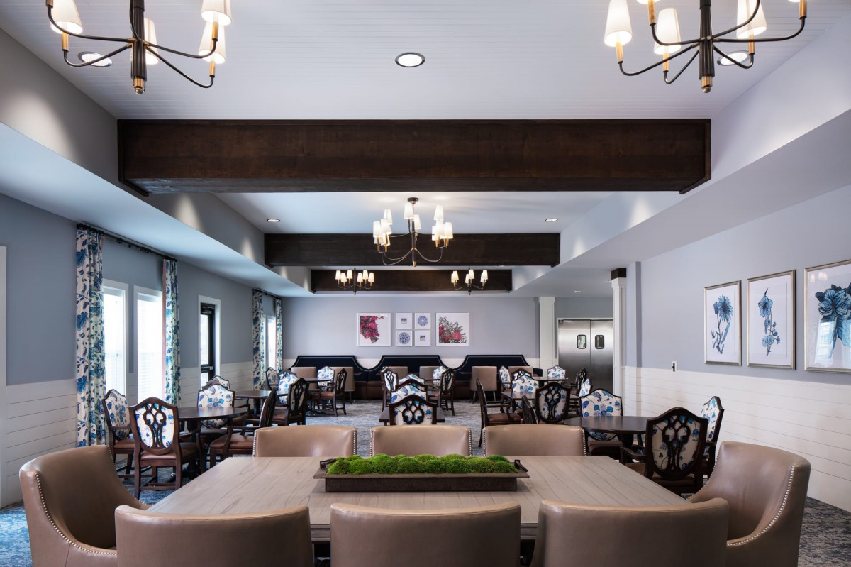 A spacious dining room with elegant chandeliers and stylish furniture.