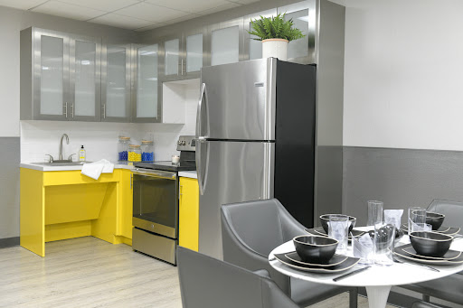 A contemporary kitchen featuring sleek stainless steel appliances and vibrant yellow accents, complete with a stylish dining area.