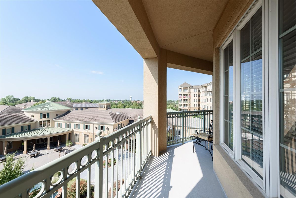 A spacious balcony with a view of surrounding buildings and a clear sky.