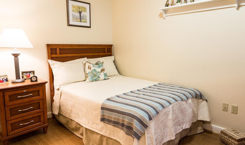 A cozy bedroom with a neatly made bed, featuring decorative pillows and a throw blanket.
