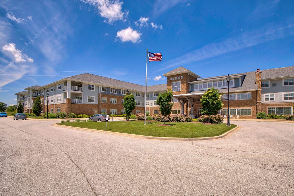A modern building with an American flag flying in front, set against a partly cloudy sky.