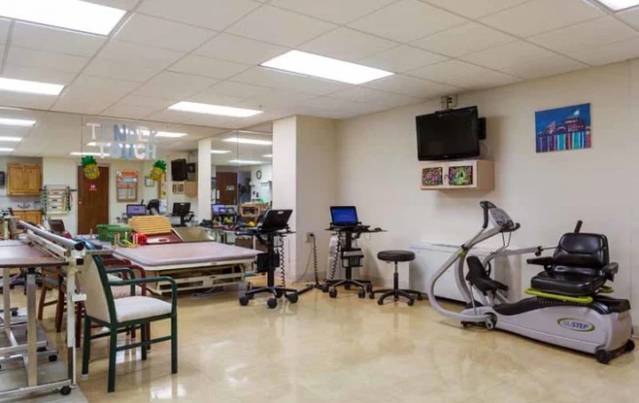 A rehabilitation room equipped with physical therapy machines and exercise tables.