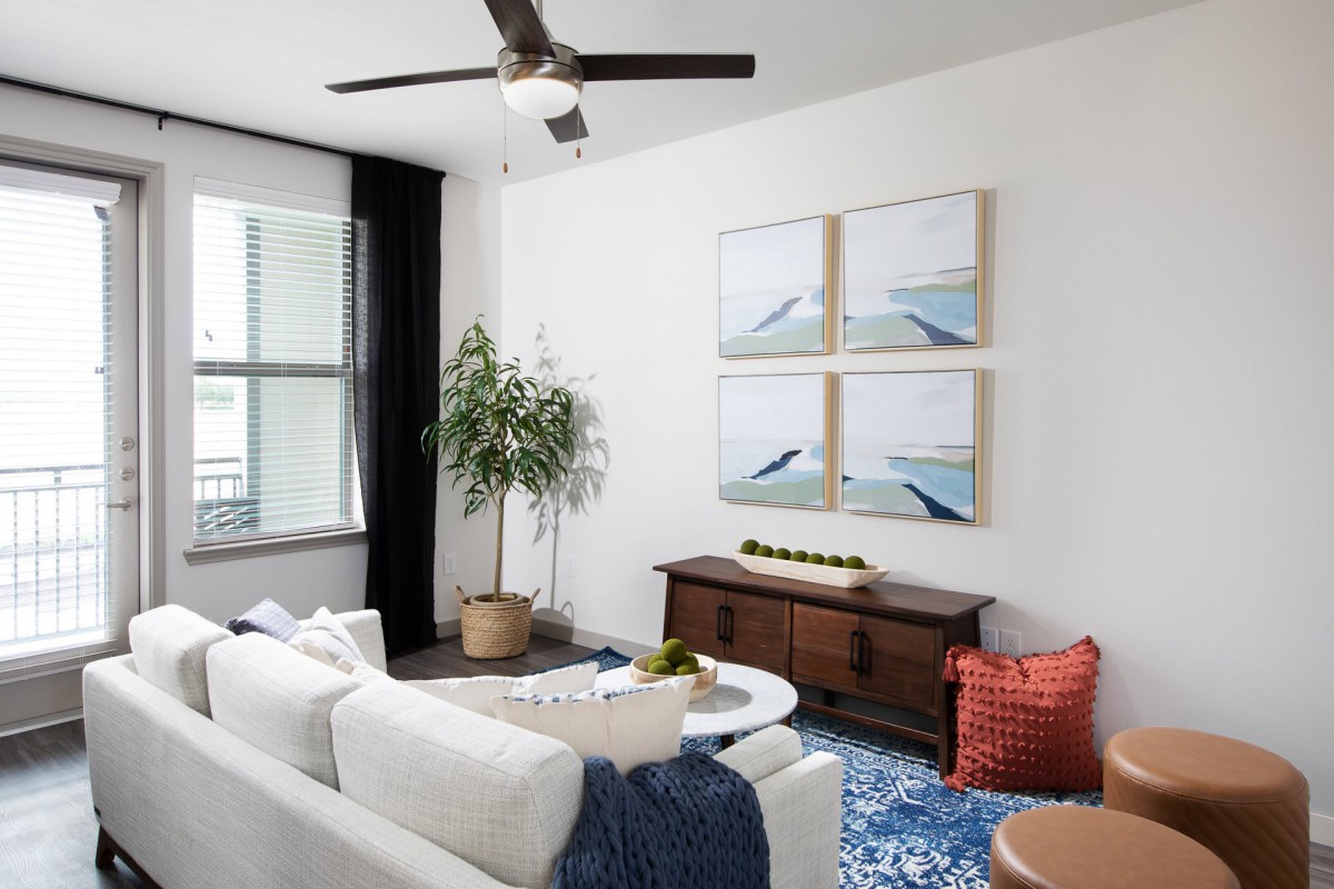 A modern living room with a white sofa, coffee table, and wooden furniture, featuring wall art and a potted plant for decor.