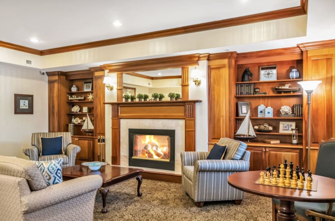 A cozy living room featuring a fireplace surrounded by elegant wooden bookshelves and comfortable armchairs.