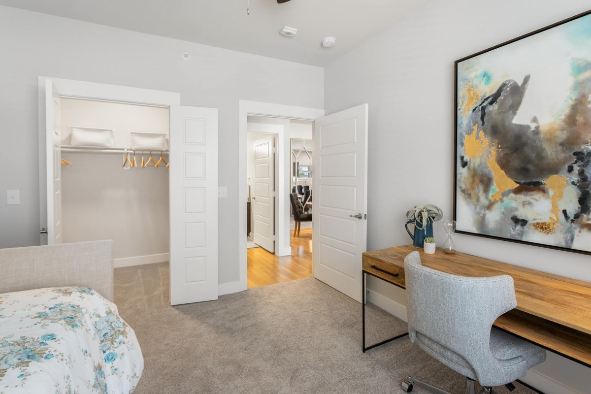 A modern bedroom with a closet, desk, and vibrant artwork on the wall.