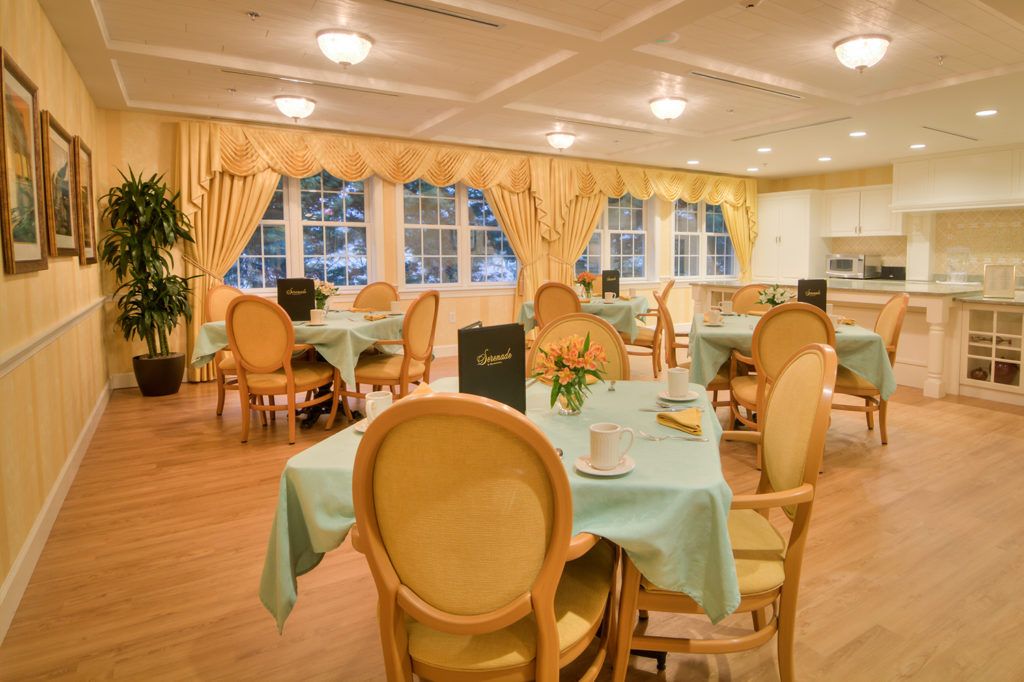 An elegantly designed dining room with neatly arranged tables and chairs, accented by large windows and stylish curtains.