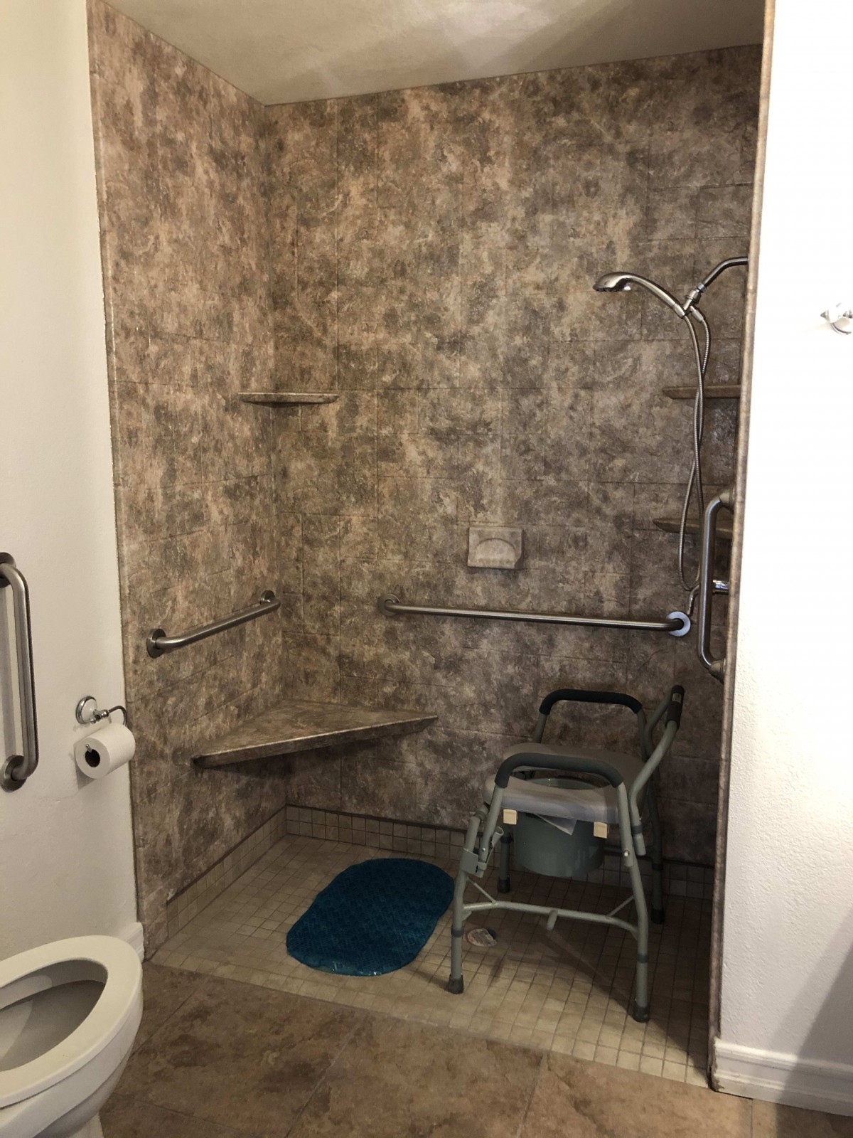 An accessible bathroom with a shower, grab bars, and a shower chair for ease of use.